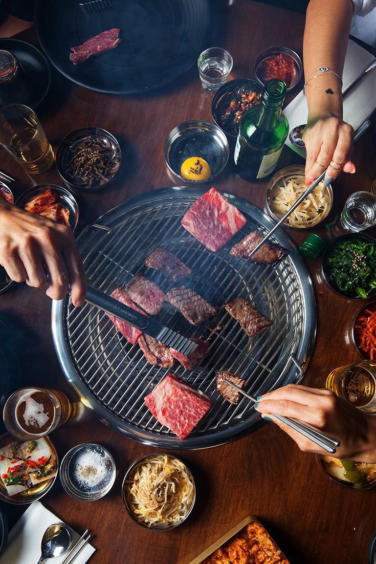 Marbled beef searing over charcoal as diners grill at the table